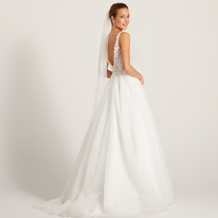 Robe de mariée Coline de chez Lily. Robe en dentelle et perles sur le bustier et une jupe en tulle fluide et léger. Un décolleté devant et dos échancré.